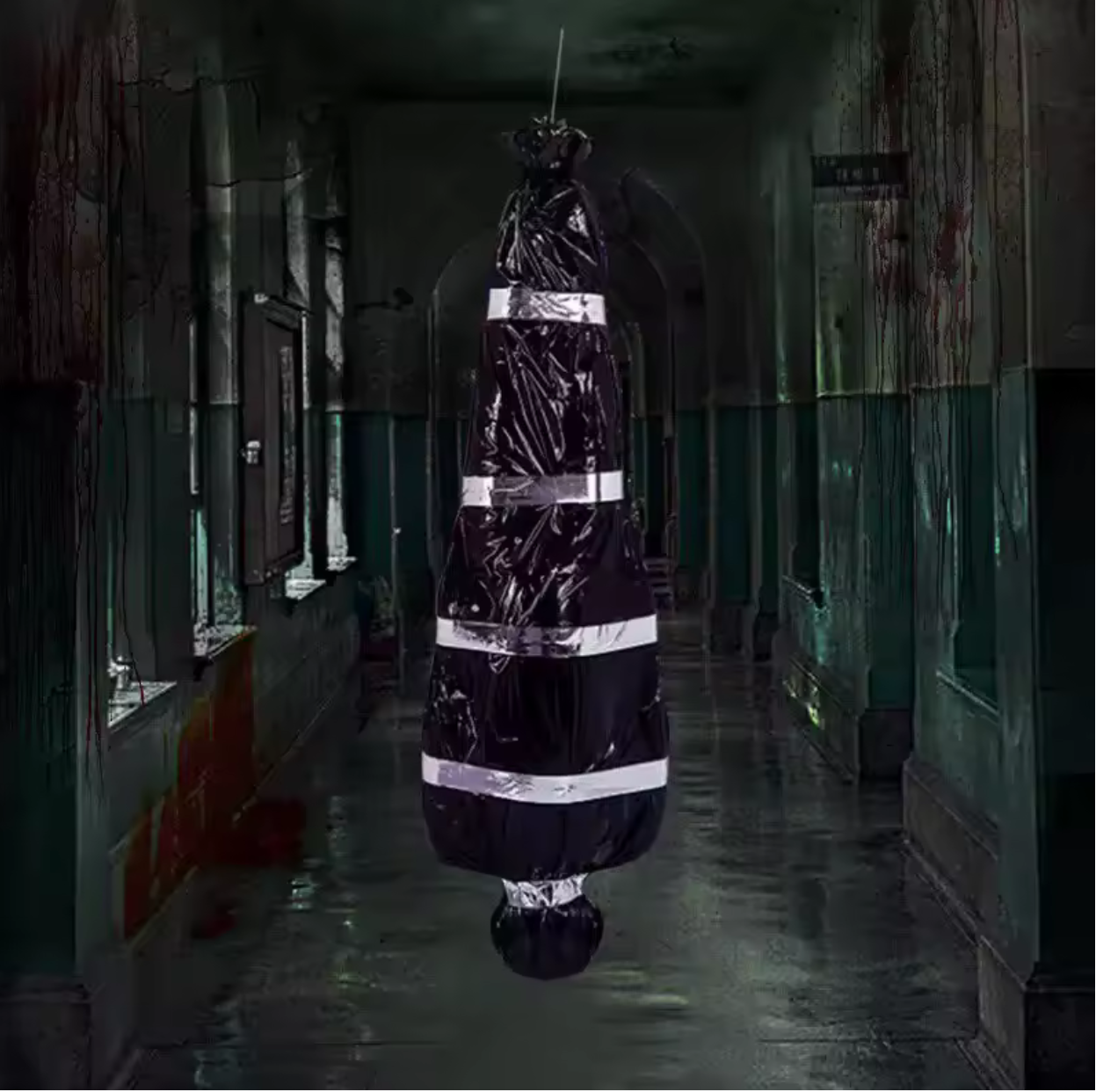 A black plastic-covered hanging object wrapped with reflective silver tape, suspended in a dark, eerie hallway with wet floors and distressed walls.
